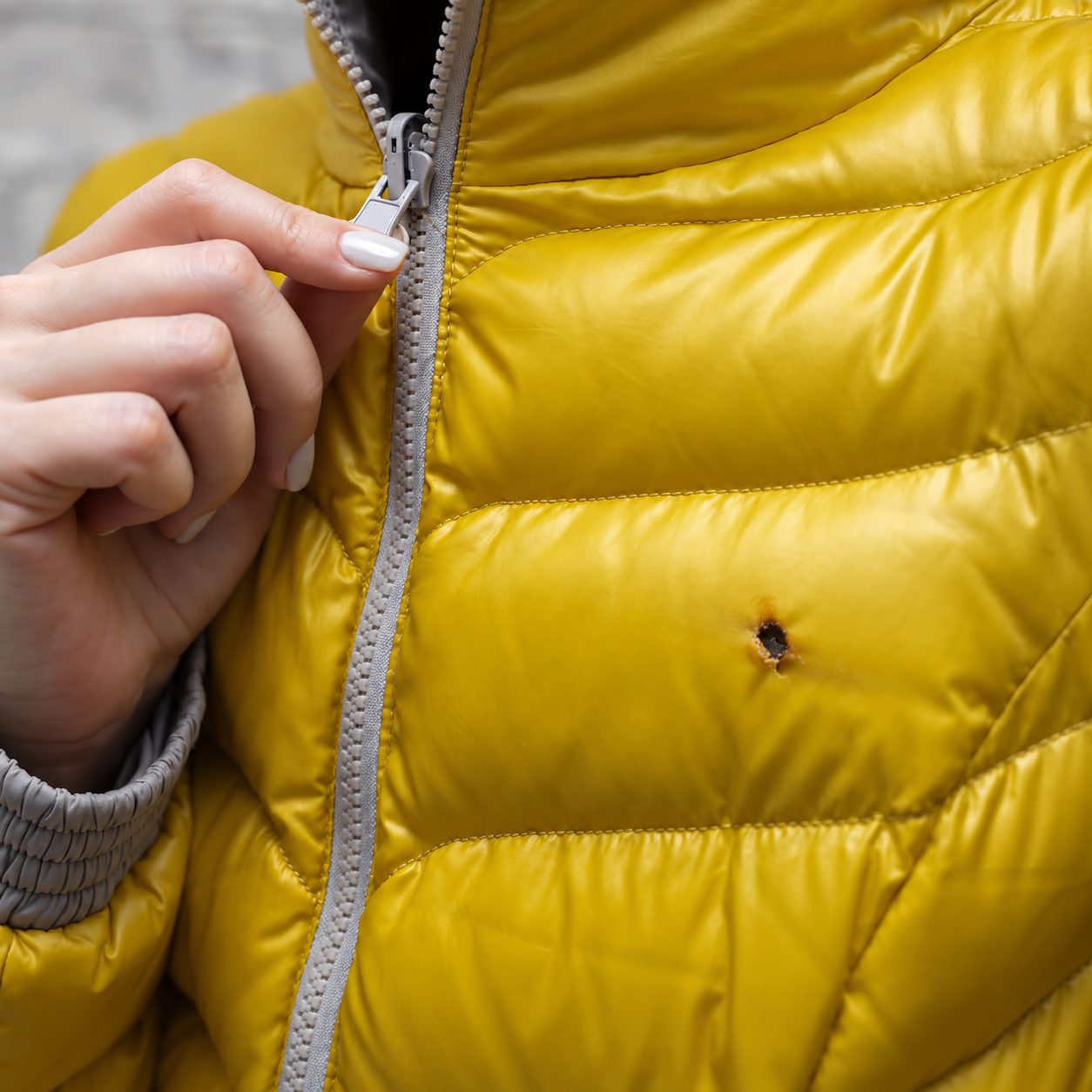 Gelbe Steppjacke mit Brandloch